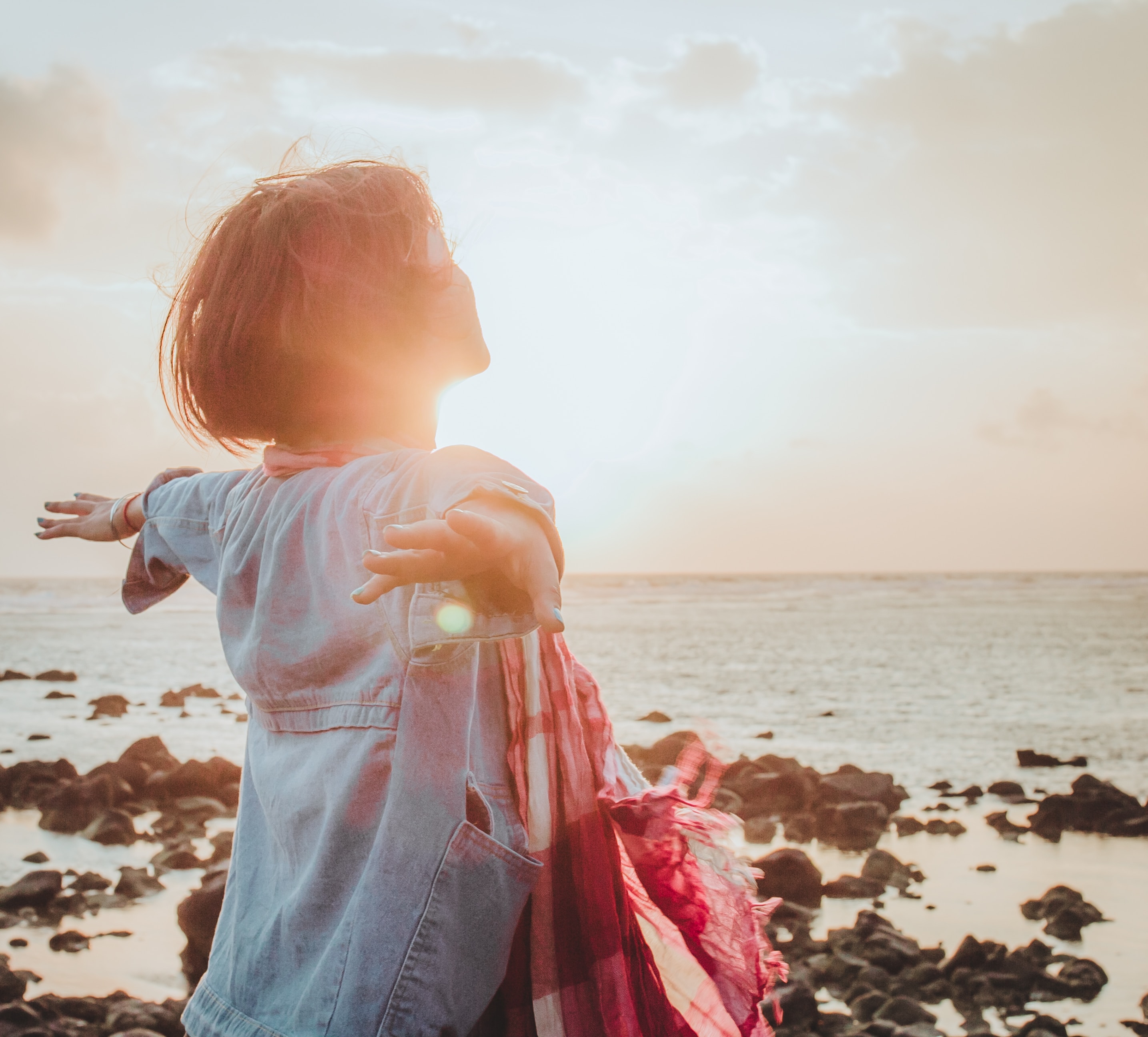 Woman with her arms open facing the sun.